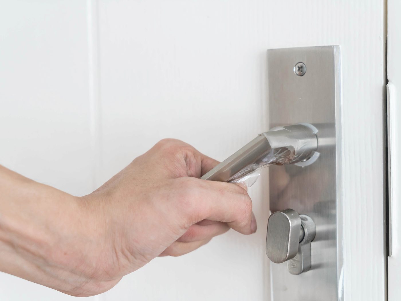 A locksmith fitting a lock on a white front door